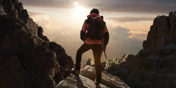 A mountain climber ascends a mountain to its peak